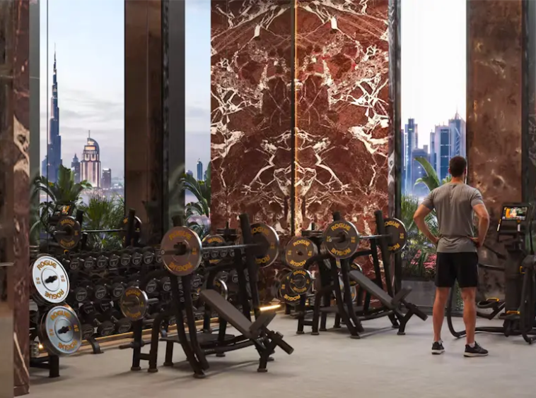 Resident exercising inside the fully equipped gym at Binghatti Spectre with views of the Dubai skyline